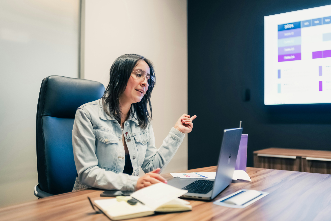 A woman gestures as she presents a slide to her colleauges on Zoom.